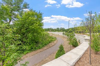 A pathway with a wall on one side and trees on the other.